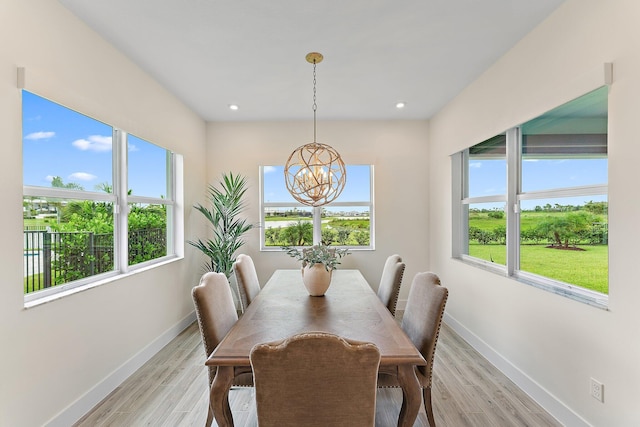 dining space with light wood-type flooring, an inviting chandelier, and a healthy amount of sunlight