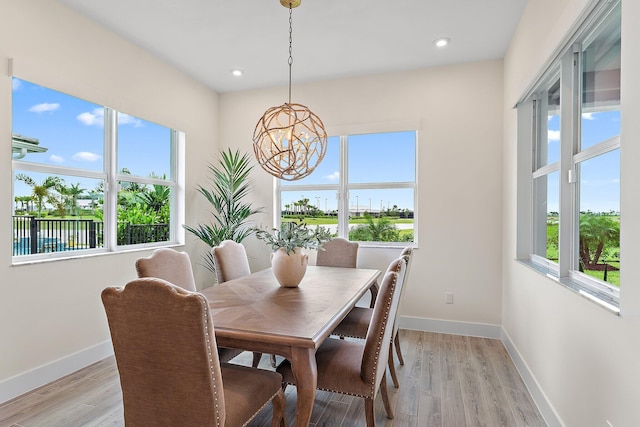 dining space with a water view, an inviting chandelier, and light hardwood / wood-style flooring