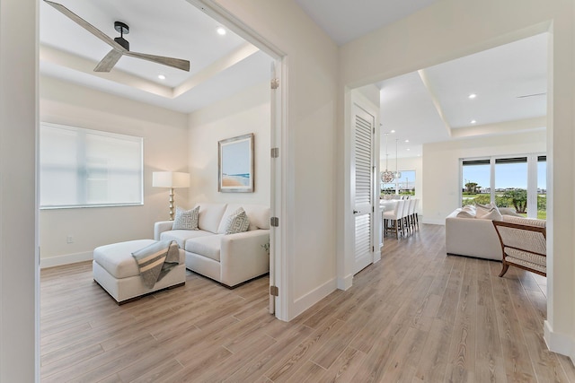 interior space with light wood-type flooring, a tray ceiling, and ceiling fan