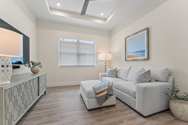 living room with light wood-type flooring and a tray ceiling