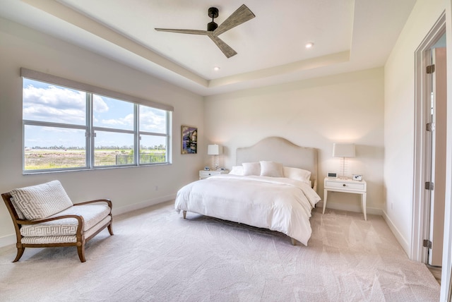 bedroom featuring a raised ceiling, ceiling fan, and carpet