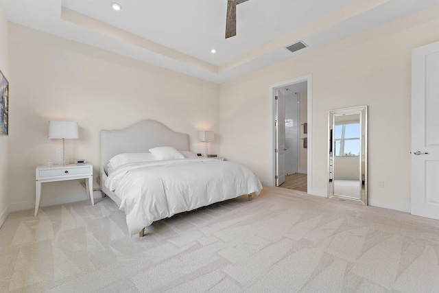 bedroom featuring a raised ceiling, ceiling fan, and light carpet