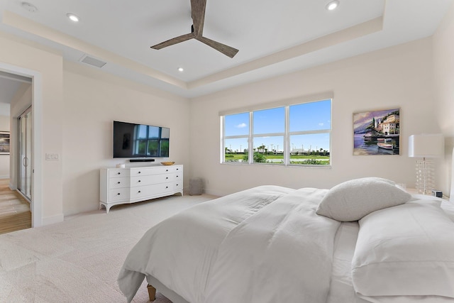 bedroom featuring a raised ceiling, ceiling fan, and light hardwood / wood-style flooring