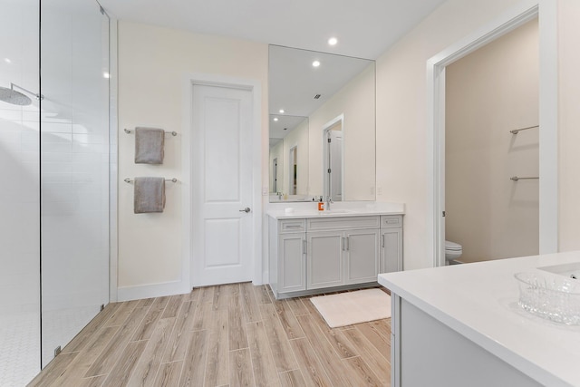 bathroom featuring toilet, walk in shower, hardwood / wood-style flooring, and vanity