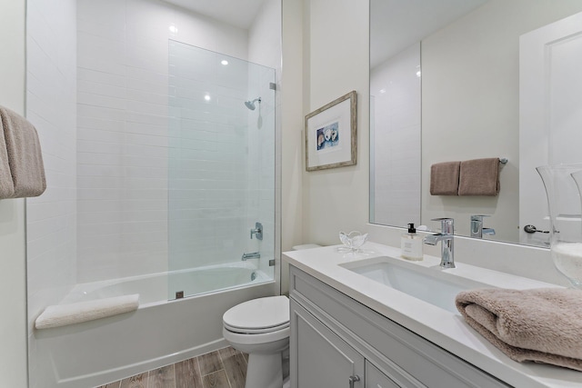 full bathroom featuring hardwood / wood-style floors, tiled shower / bath, toilet, and vanity