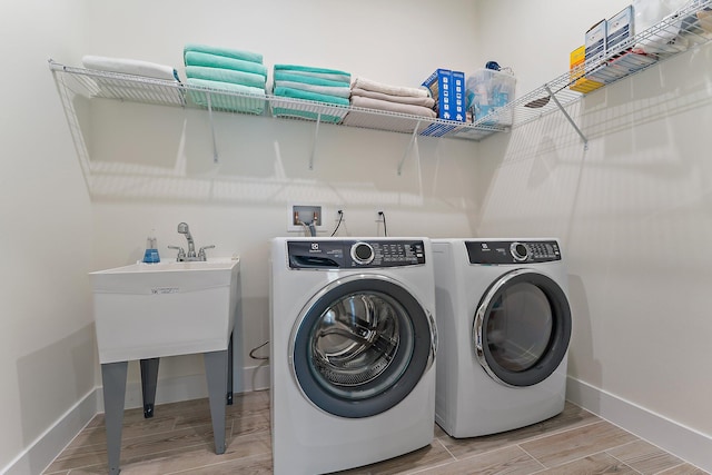 laundry room with washing machine and clothes dryer and light hardwood / wood-style floors