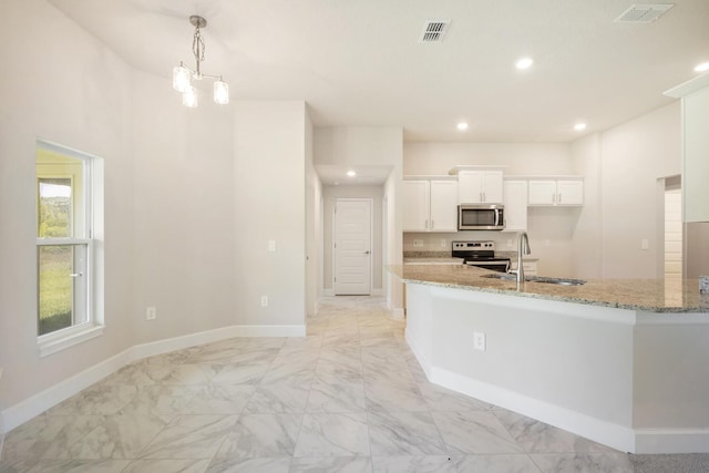 kitchen with pendant lighting, sink, light stone counters, white cabinetry, and stainless steel appliances