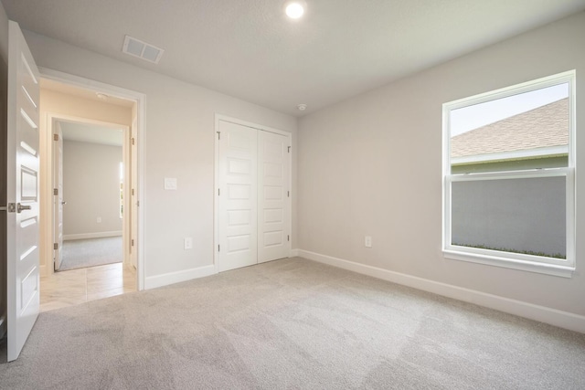 unfurnished bedroom featuring light colored carpet and a closet