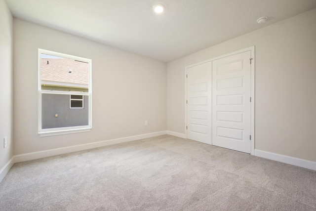 unfurnished bedroom with light carpet and a closet