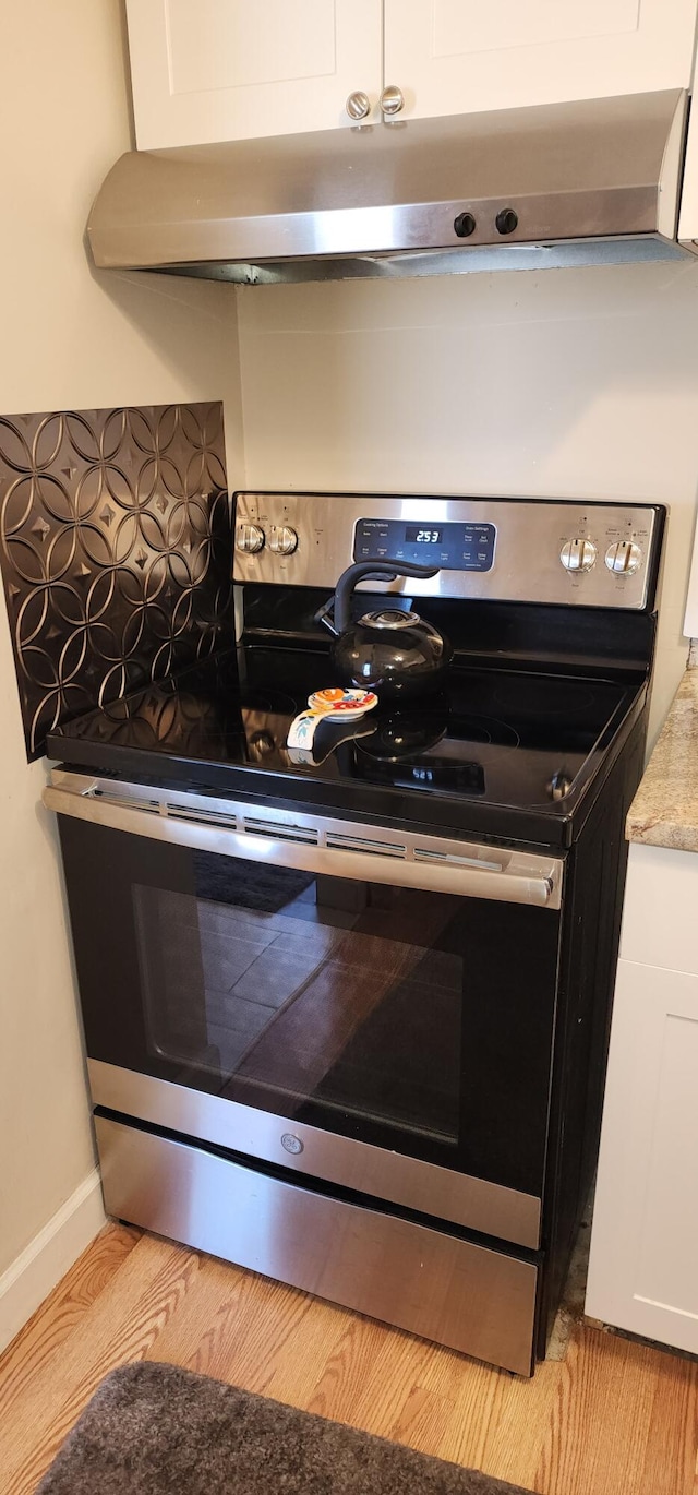 kitchen featuring white cabinetry, stainless steel electric range oven, and light hardwood / wood-style flooring