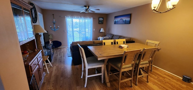 dining space featuring ceiling fan with notable chandelier and hardwood / wood-style flooring