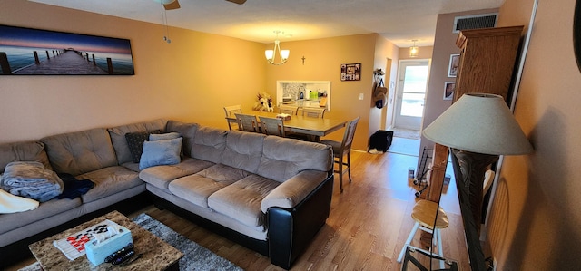 living room with ceiling fan with notable chandelier and hardwood / wood-style flooring