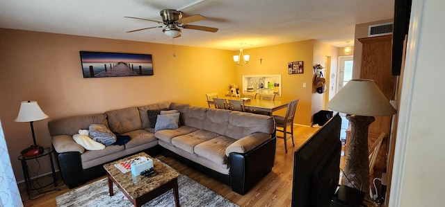 living room with ceiling fan with notable chandelier and hardwood / wood-style floors