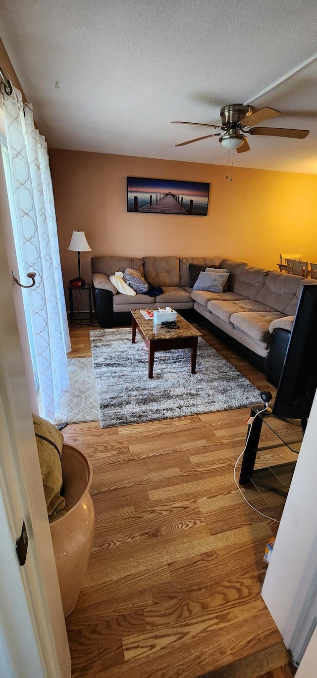 living room with a textured ceiling, ceiling fan, and hardwood / wood-style floors