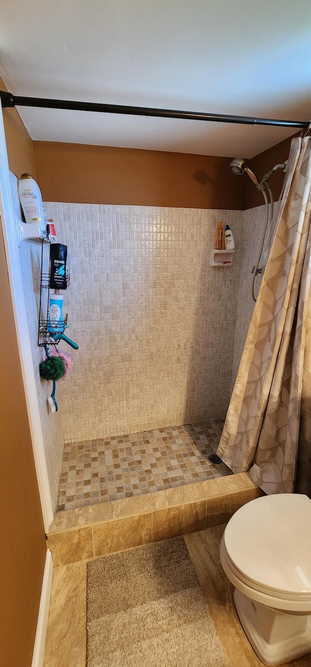 bathroom with tile patterned flooring, toilet, and a shower with shower curtain