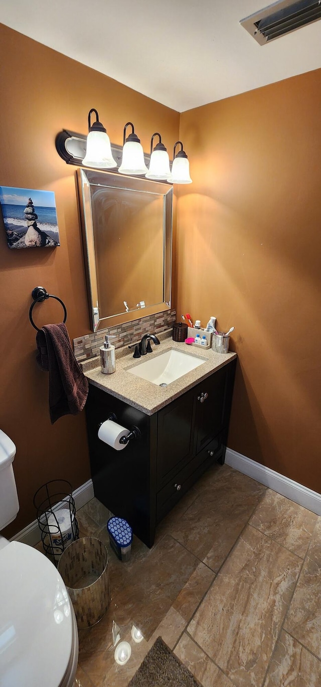 bathroom featuring tile patterned flooring, decorative backsplash, vanity, and toilet