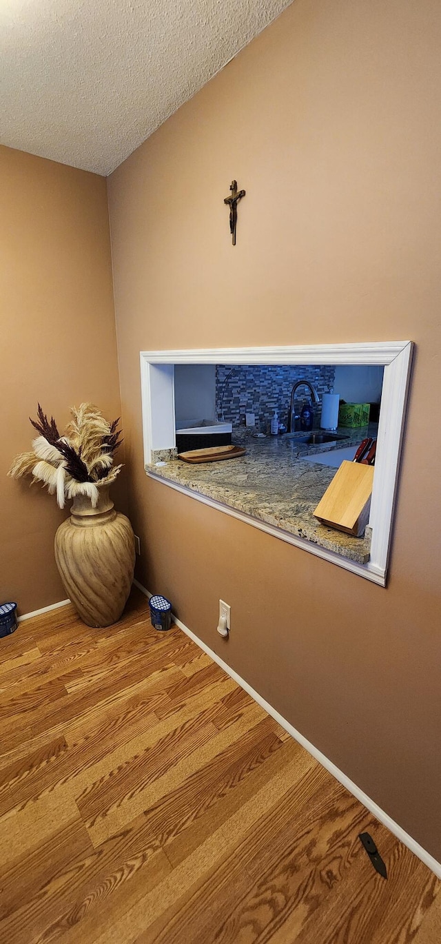 room details featuring a textured ceiling, hardwood / wood-style flooring, and sink