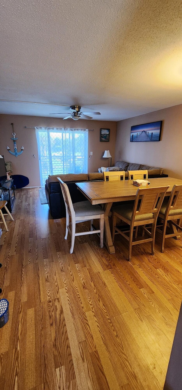 dining room featuring a textured ceiling, ceiling fan, and hardwood / wood-style floors