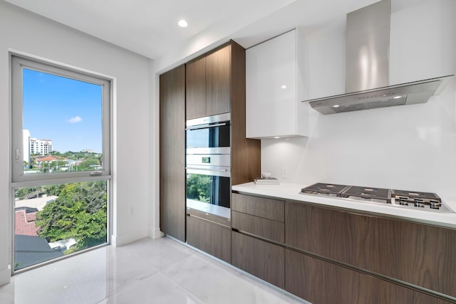 kitchen featuring ventilation hood, double wall oven, a healthy amount of sunlight, cooktop, and light tile patterned floors