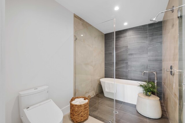 bathroom with tile patterned flooring, toilet, a shower with door, and tile walls