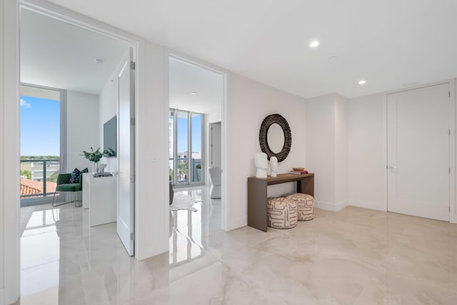 hall featuring marble finish floor, expansive windows, baseboards, and recessed lighting