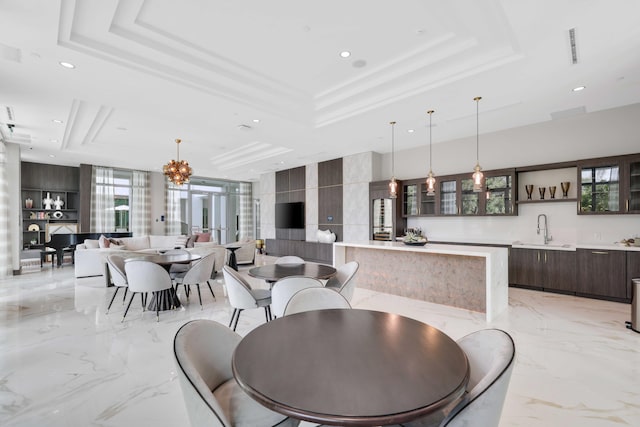 dining space featuring sink, a tray ceiling, a notable chandelier, and light tile patterned floors