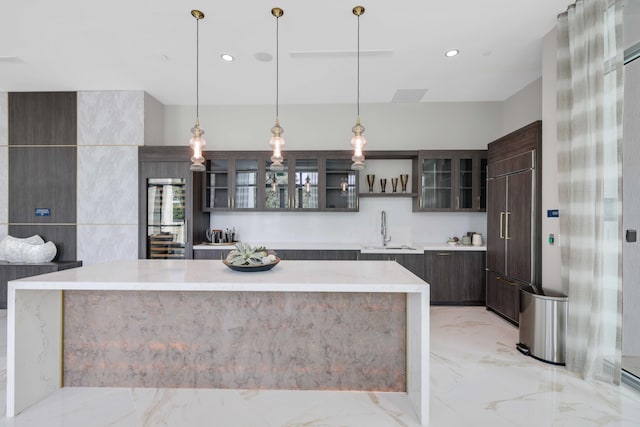 kitchen with paneled built in refrigerator, a sink, marble finish floor, dark brown cabinets, and modern cabinets