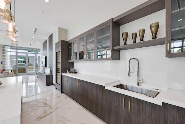 kitchen with sink, decorative light fixtures, light tile patterned flooring, and dark brown cabinetry