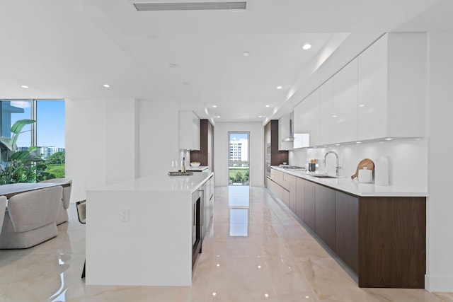 kitchen featuring tasteful backsplash, white cabinetry, light tile patterned floors, sink, and dark brown cabinets