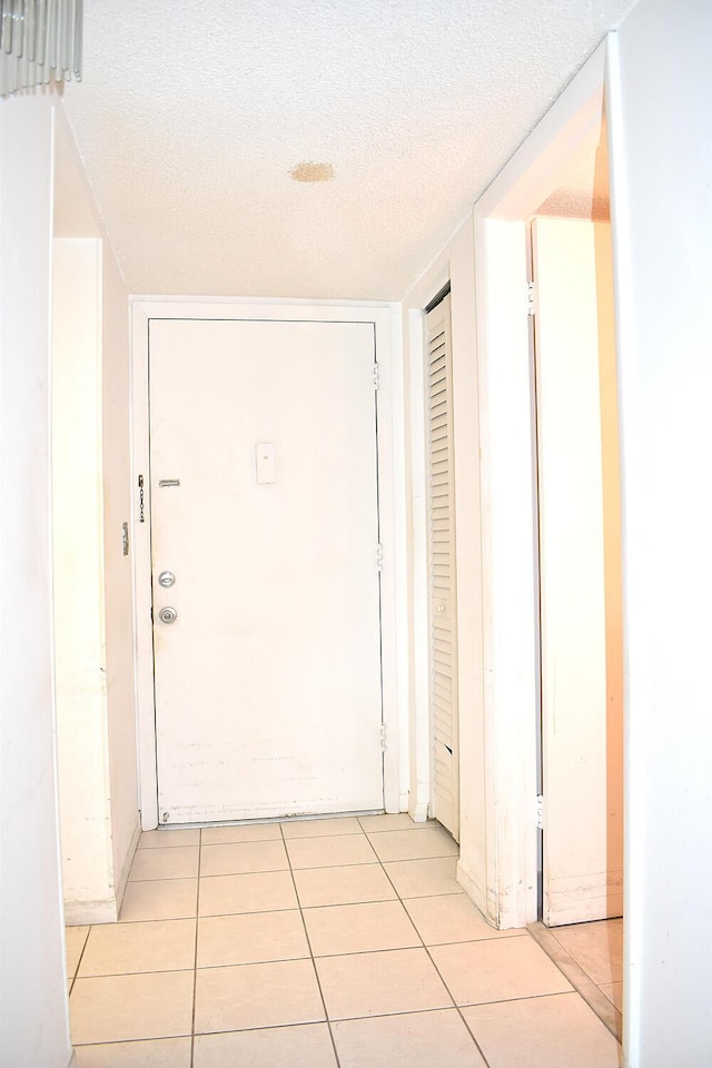 corridor with light tile patterned floors and a textured ceiling