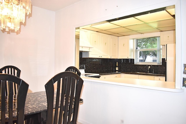 kitchen featuring sink, range, white refrigerator, tasteful backsplash, and white cabinets