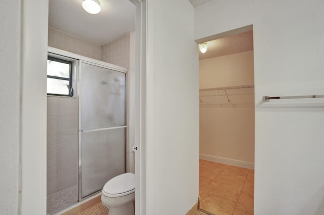 bathroom featuring tile patterned flooring, toilet, walk in shower, and a textured ceiling