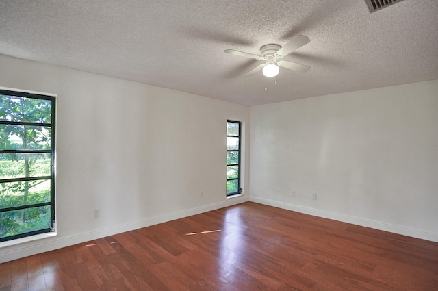 empty room featuring ceiling fan, dark wood-type flooring, and a textured ceiling