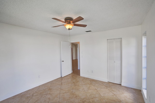 tiled empty room with ceiling fan and a textured ceiling