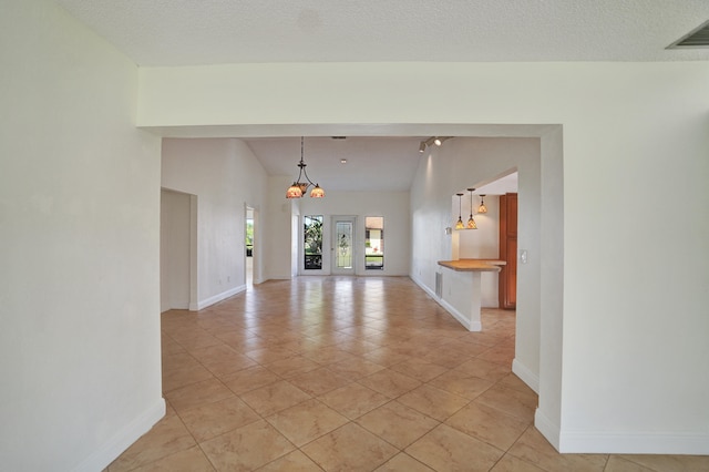 unfurnished living room with light tile patterned floors, a textured ceiling, and an inviting chandelier