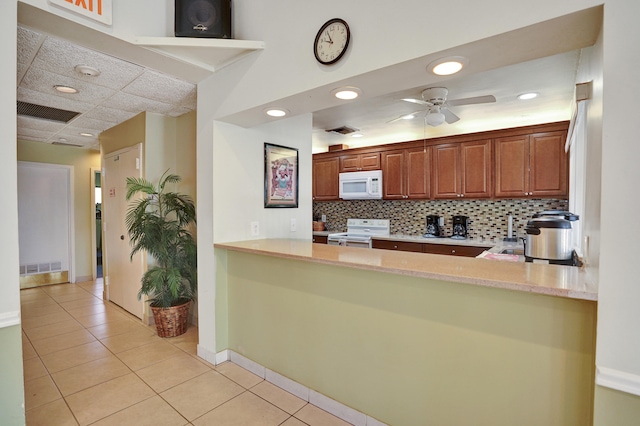 kitchen with kitchen peninsula, light tile patterned floors, white appliances, and ceiling fan