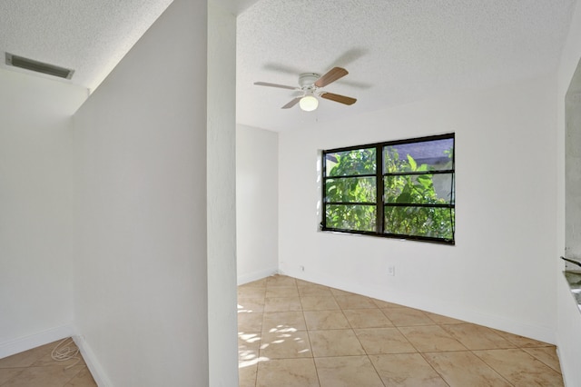 empty room featuring light tile patterned floors, a textured ceiling, and ceiling fan