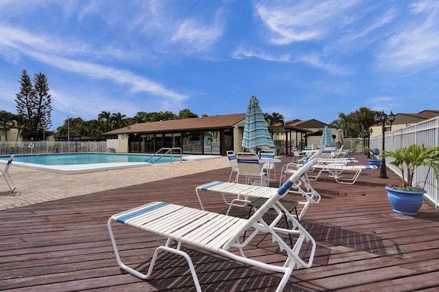 community pool with a patio area, fence, and a deck