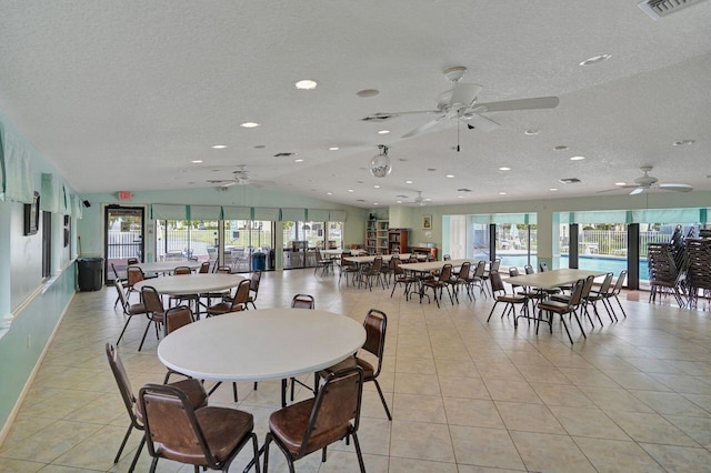 dining room with lofted ceiling, a textured ceiling, plenty of natural light, and light tile patterned flooring