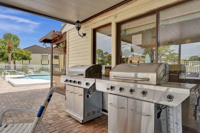 view of patio / terrace with exterior kitchen, a fenced in pool, fence, and area for grilling