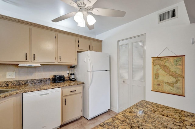 kitchen with light tile patterned floors, visible vents, cream cabinets, dark stone counters, and white appliances