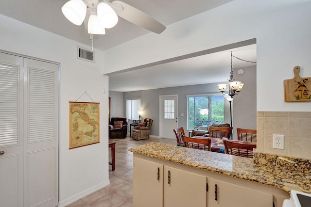 kitchen with light tile patterned flooring, visible vents, open floor plan, light stone countertops, and pendant lighting