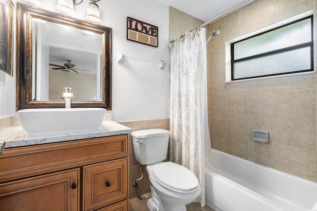 full bath with ceiling fan, toilet, a wainscoted wall, shower / tub combo, and vanity