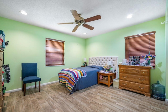 bedroom featuring baseboards, ceiling fan, a textured ceiling, and light wood finished floors