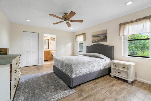 bedroom with a closet, ensuite bath, ceiling fan, and hardwood / wood-style flooring