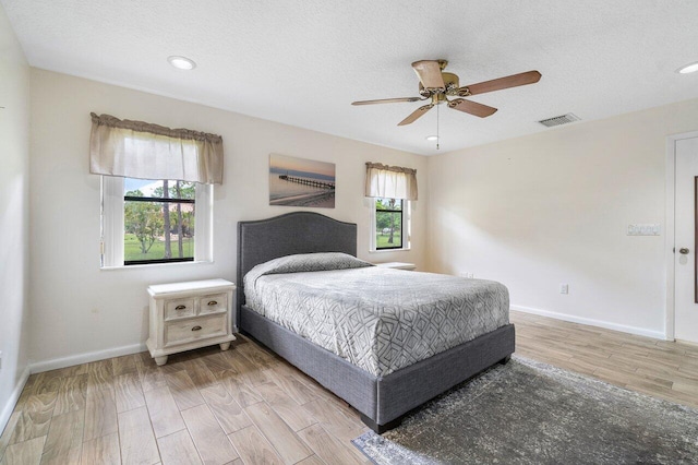 bedroom featuring ceiling fan, hardwood / wood-style flooring, and a textured ceiling