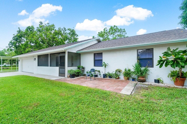 rear view of house featuring a sunroom, a garage, and a yard