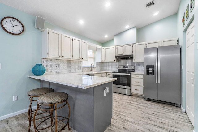 kitchen featuring stainless steel appliances, light wood-type flooring, and kitchen peninsula