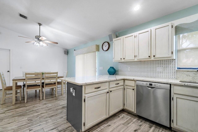 kitchen featuring visible vents, a peninsula, vaulted ceiling, stainless steel dishwasher, and backsplash