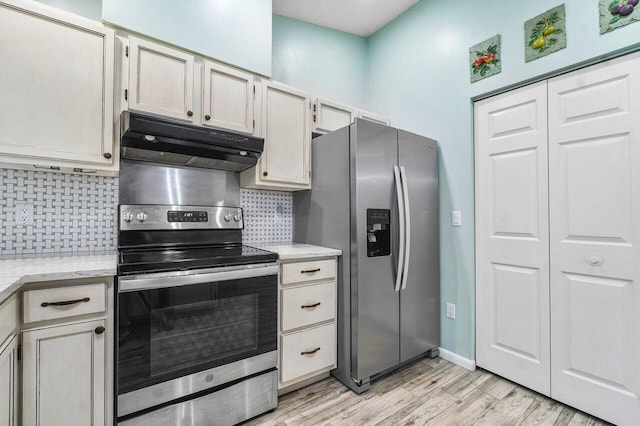 kitchen with decorative backsplash, light wood-style flooring, light stone countertops, stainless steel appliances, and under cabinet range hood